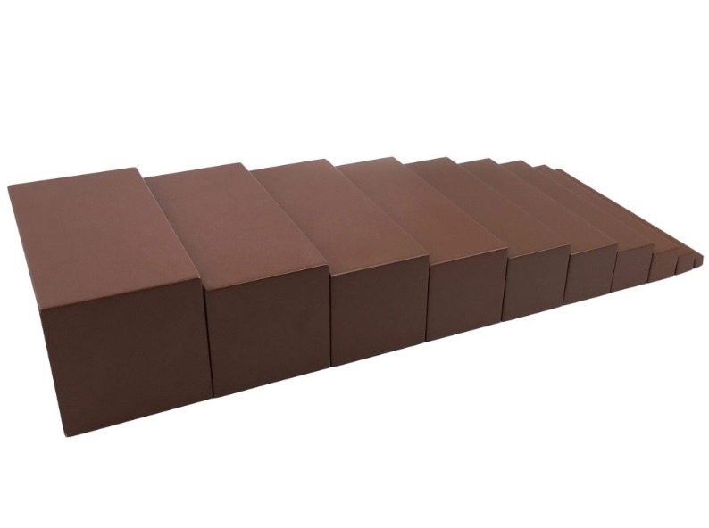 Child working with brown stair prisms in Montessori classroom